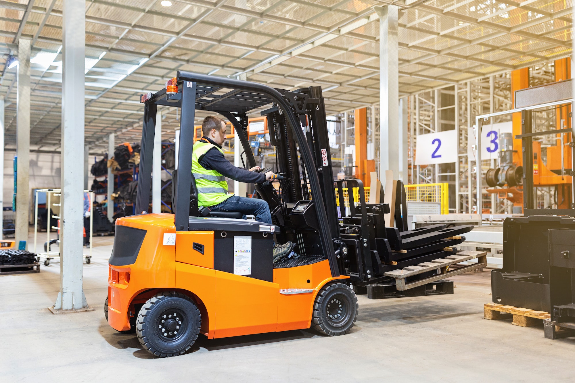 Magazijnmedewerker in uniform aan het werk op vorkheftruck in modern automatisch magazijn