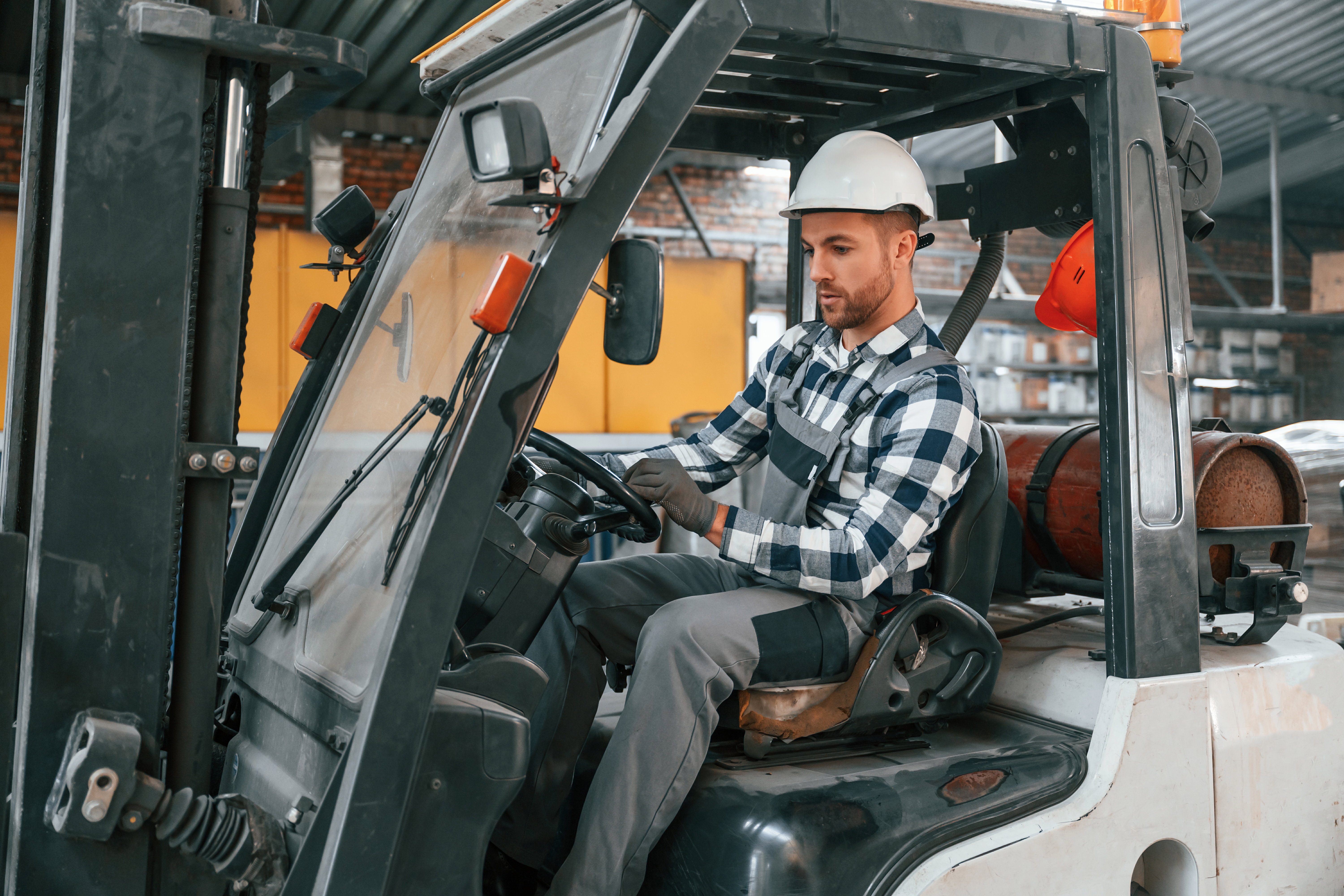 Heftruckchauffeur. Mannelijke fabrieksarbeider in uniform is binnen