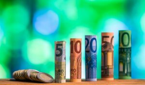 Five, ten, twenty, fifty and one hundred euro rolled bills, with euro coins on green
