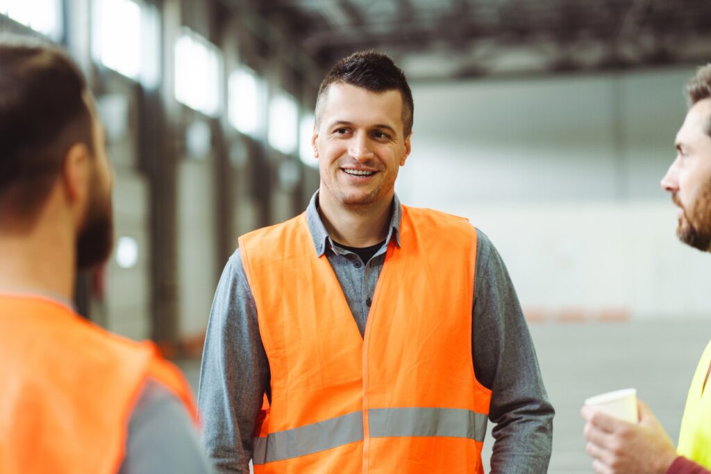 Oferty pracy w Holandii 1 Attractive, smiling man, foreman wearing workwear, talking with colleagues, standing in warehouse