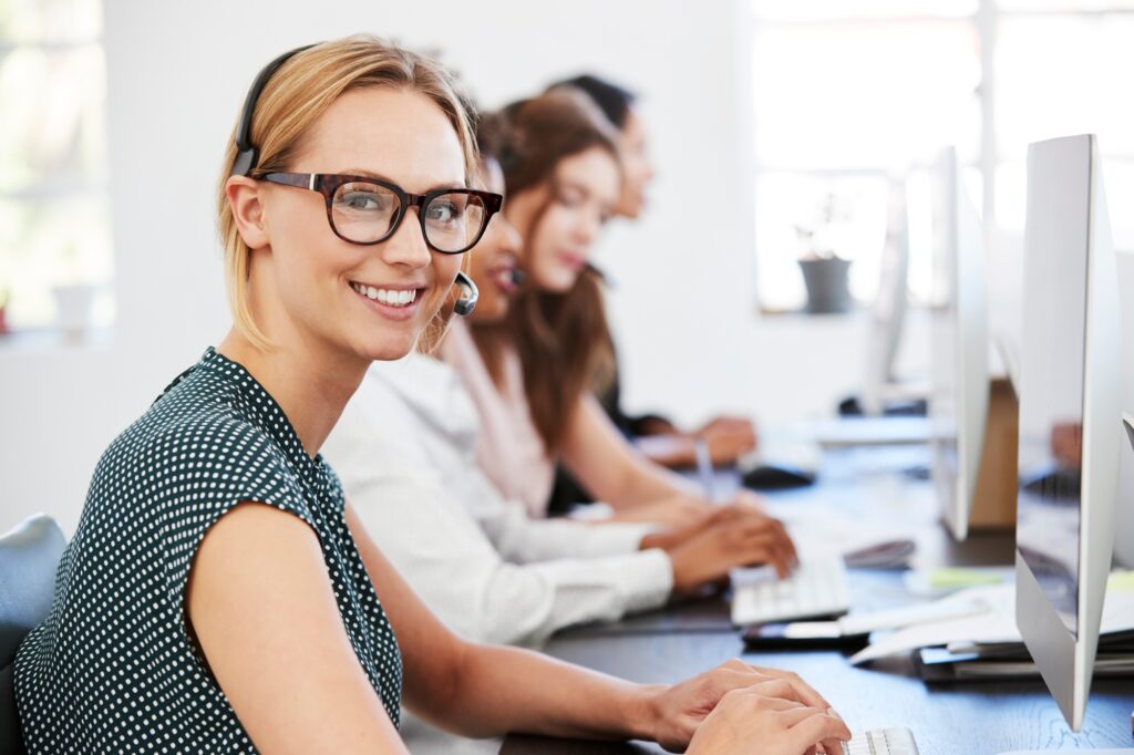 Oferty pracy w Holandii 2 Young white woman with headset smiling to camera in office